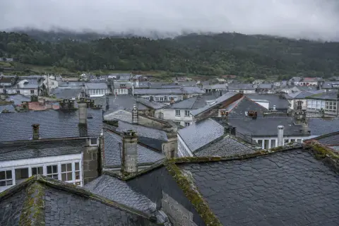 Panorámica de cubiertas de pizarra con chimeneas de granito y galerías blancas entre ellas